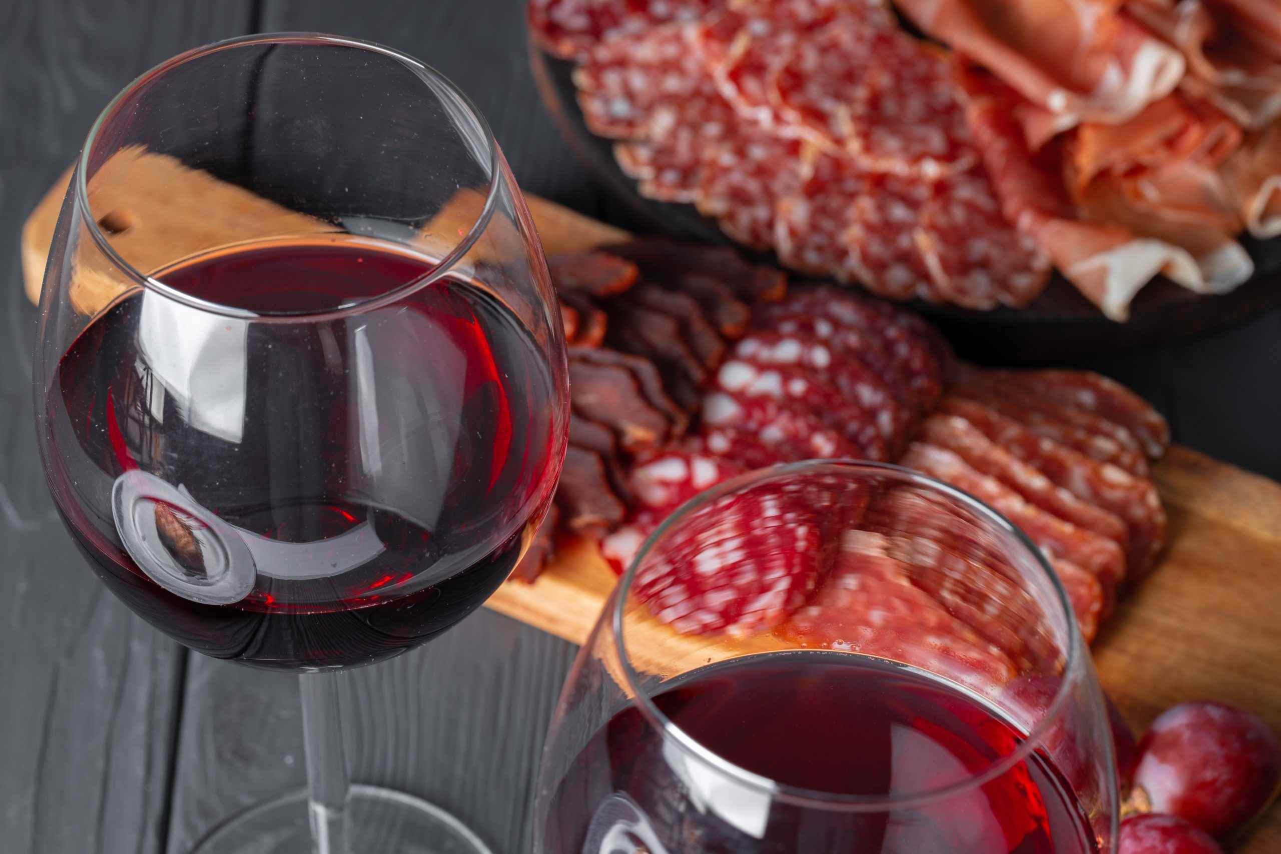 Wineglass with red wine and meat cuts board
